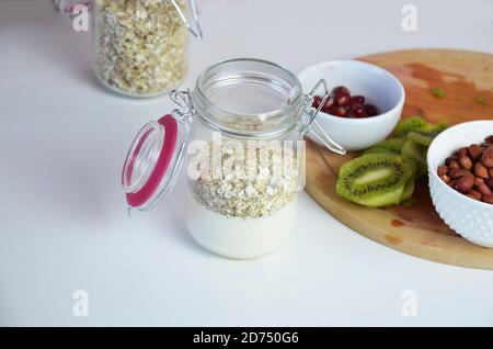 Healthy breakfast overnight oats with fresh berries in a glass jar with dried fruits, apple and nuts, walnuts, almonds. with yogurt, cottage cheese, p Stock Photo