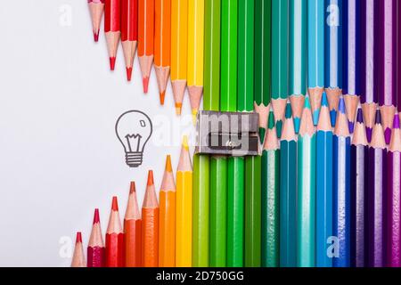 Colour pencils organized in the shape of a zipper opening up to a light bulb as a symbol of creativity Stock Photo