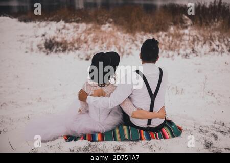 groom and bride sitting on a Mexican national veil on a snowy hill Stock Photo