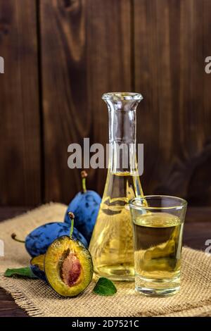 Plum brandy or schnapps in glasses with fresh and tasty plums on a wooden table. Selective focus. Stock Photo