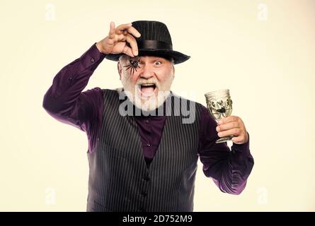 Halloween is not just for candy anymore. evil wizard cooking magic potion with spider. man magician in witch hat. barman make cocktail for halloween party. halloween holiday costume. happy halloween. Stock Photo