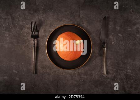 Vintage template with old metal plate with pumpkin on black stone background for Halloween design. Fall concept. Halloween celebration concept. Flat lay style. Stock Photo