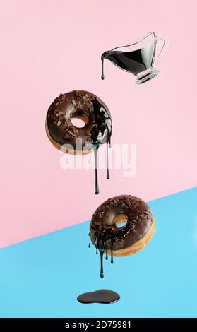Flying donuts with dripping chocolate on pink blue background. Pop art design Stock Photo