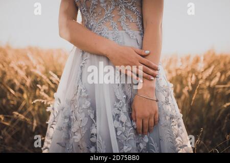 girl in a gray dress with flowers shows her beautiful blue manicure Stock Photo