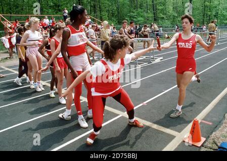 The baton hand off pass in a girls track meet shows the importance of teamwork Stock Photo