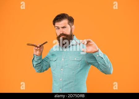 Classic values. Retro barbershop. Hipster with tools. Designing haircut. Fresh hairstyle. Barbershop concept. Barbershop salon. Personal stylist. Vintage barber. Bearded man hold razor and scissors. Stock Photo