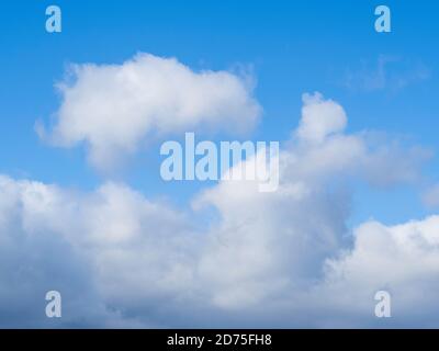 A cloudscape with a bigger wispy cloud as the basis of the frame and a smaller cloud on top on a light blue sky.