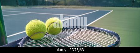 Tennis court panorama background with blue racket and two tennis balls ready to play match on outdoor courts summer sport lifestyle. Mobile photo Stock Photo