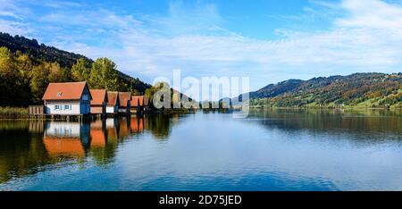 View on big, Grosser Alpsee lake by Immenstadt im in Allgau with wooden hauses, blue sky. Bavaria, Germany Stock Photo