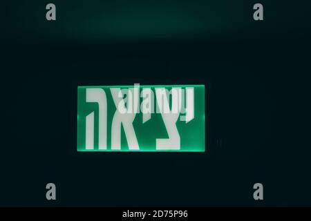 Glowing green Exit sign on Hebrew in Israel, evacuation, safety, office building sign. Green emergency exit sign. Stock Photo