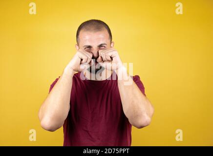 Russian man wearing basic red t-shirt over yellow insolated background depressed and worry for distress, crying angry and afraid. Sad expression. Stock Photo