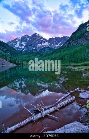 Maroon Bells in Aspen Colorado at Sunset. Beautiful maroon colors and pink clouds reflecting off glassy water. Reflection of mountain tops on water fr Stock Photo