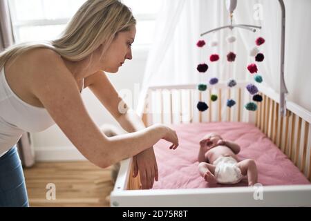 mother suffering from postnatal depression near crib with cute baby at home Stock Photo