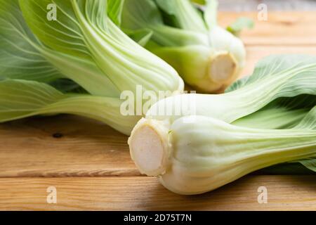 Fresh green bok choy or pac choi chinese cabbage on a brown wooden background. Side view, close up. Stock Photo