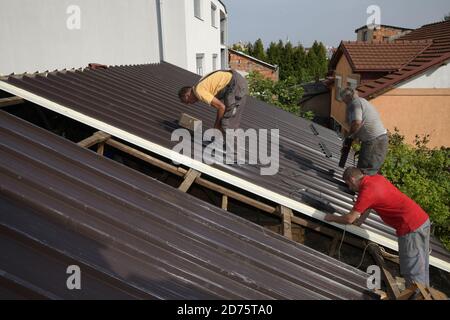 Three workers roofer builder working on roof structure on construction site Stock Photo