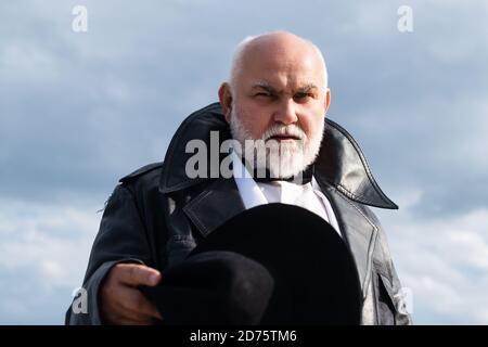 Senior fashion man. Stylish and fashion bearded aged man in leather jacket coat and modern hat. Business style. Fashionable male. Stock Photo