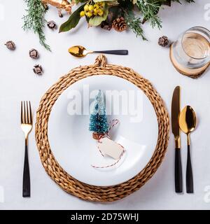 Elegant Christmas place settings with gold and white decoration and golden cutlery. Pine tree figurine on the dish from above Stock Photo