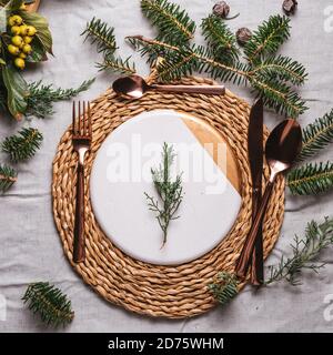 Christmas table settings with a wreath, pine branch and golden cutlery from above, Holiday dinner Stock Photo