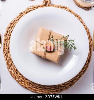 Elegant Christmas place settings with gold and white decoration and golden cutlery. gift box on the dish from above Stock Photo