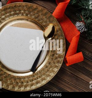 Holiday Gold place setting, table decorated with natural pine branches, and red lace on wooden background, from above. Ideas for the Christmas table o Stock Photo