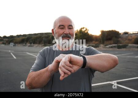 an old man with white hair and beard is looking at his smart watch Stock Photo