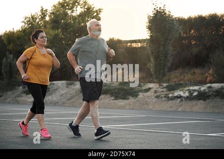 A woman and an elderly man are jogging in the street Stock Photo
