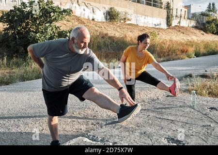 A middle-aged couple do leg stretching in the park Stock Photo