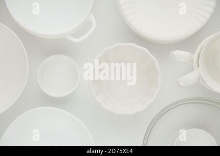 The image of white dishes of different sizes on a white shelf in the s Stock Photo