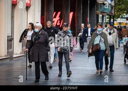 BELGRADE, SERBIA - AUGUST 29 2020: Old woman walking with cruntches with face mask protective equipment on Coronavirus Covid 19 crisis next to young m Stock Photo