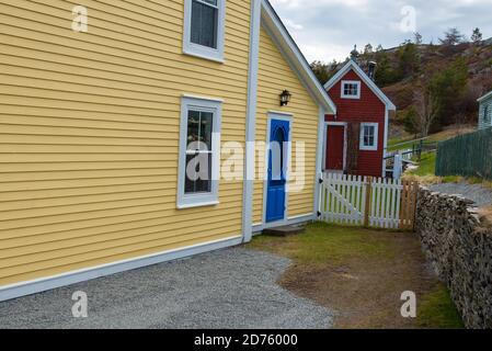 A bright blue cottage screen door on the exterior of a yellow building with closed double hung glass windows. Stock Photo