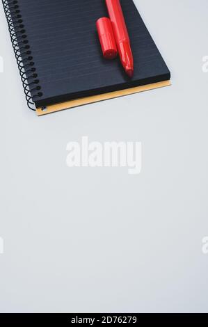 Vertical shot of a notebook and a marker on a blue surface Stock Photo