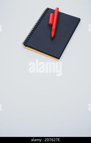 Vertical shot of a notebook and a marker on a blue surface Stock Photo