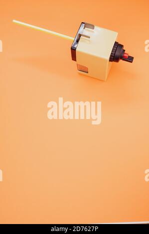 Vertical shot of a mechanical pencil sharpener on an orange surface Stock Photo