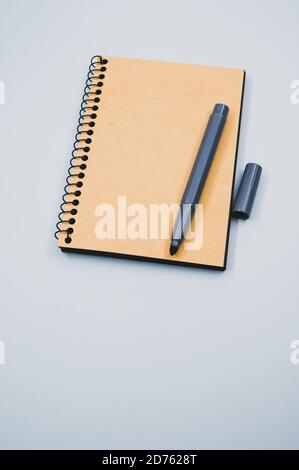 Vertical shot of a notebook and a marker on a blue surface Stock Photo