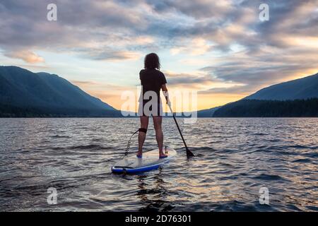 Woman Paddleboarding on Scenic Lake at Sunset