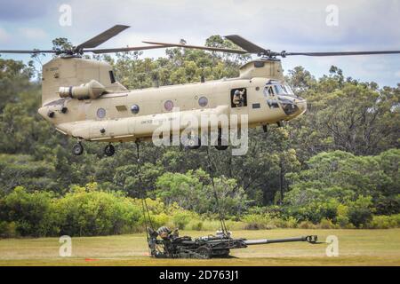 SCHOFIELD BARRACKS, Hawaii - A 25th Infantry Division CH-47 Chinook carries a sling load with a M777 Howitzer in preparation for a capabilities demonstration for Lt. Gen. S K Saini, Vice Chief of the Army Staff of the Indian Army on Schofield Barracks East Range, Hawaii, on Oct. 19, 2020.  This visit will enhance the operational and strategic level collaboration between the two armies and builds towards a free and open USINDOPACOM Stock Photo