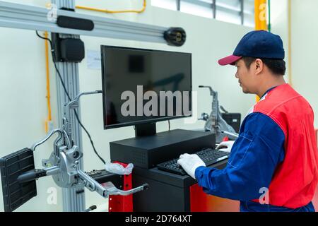 Auto mechanic or technician controls a car lift program by computer in car auto repair service center. Stock Photo