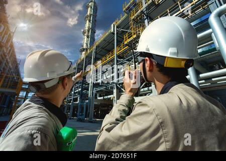 Industrial engineer or worker radio communication to the control room at oil and gas refinery plant form industry zone with sunrise and cloudy sky, oi Stock Photo