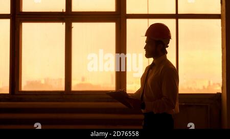 A young bearded Architect in a construction helmet on a construction site checks the result Stock Photo