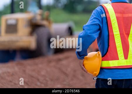 Close up Civil engineer holding helmet in road construction site, Safety first concept. Stock Photo
