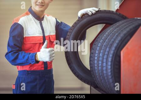 Close up technician or auto mechanic Reassuring the new standard tires in the large warehouse at auto repair service center, Stock Photo