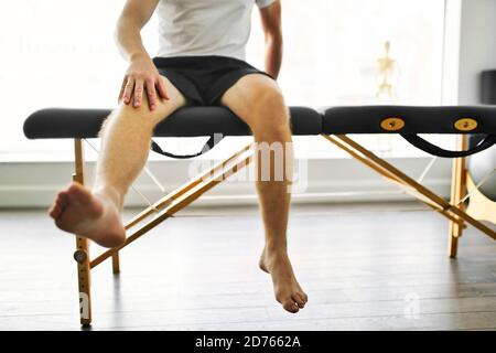 A Modern rehabilitation physiotherapy place with man client sit on table Stock Photo