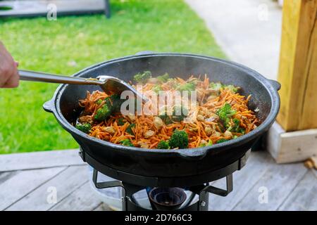 Process of cooking healthy vegetable in a cauldron over fire outside. Stock Photo