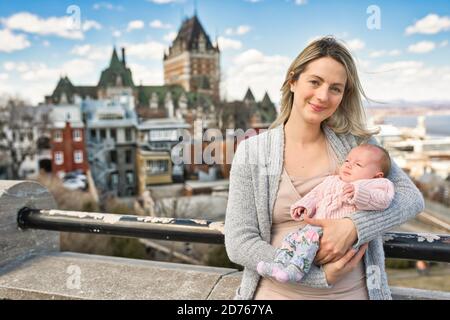 blonde women with baby at the blurred Frontenac Castle in the background, Quebec, Canada Stock Photo