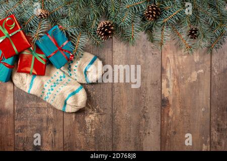 Wooden vintage Christmas background with fir branches, Christmas gifts and wool socks. Background with fir branches and Christmas set. Stock Photo