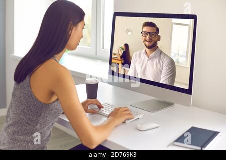Young woman sitting at computer and having video call with coworker or HR manager Stock Photo