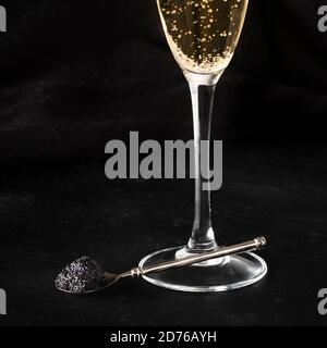Black caviar and a glass of champagne on a black background with a place for text, square shot Stock Photo