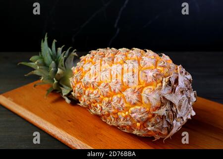 Fresh Ripe Pineapple on a Wooden Cutting Board Isolated on Black Background Stock Photo