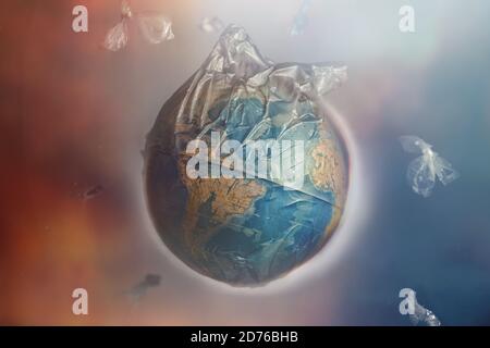 Globe of planet Earth dressed in a garbage plastic bag. Fly around the pieces of broken plastic. The concept of land pollution and ecological imbalanc Stock Photo