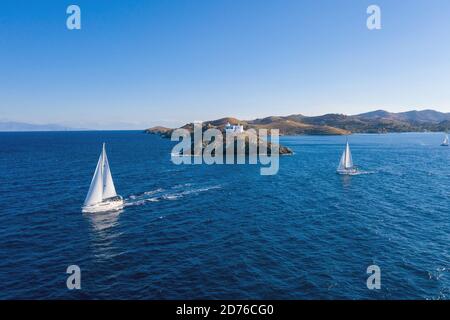 Sailing. Sailboats with white sails, rippled sea background, Lighthouse on a cape. Greece, Kea Tzia island. Summer holidays in Aegean sea. Aerial dron Stock Photo